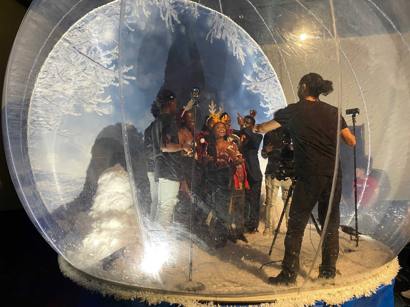 A photographer gets ready to take a still photo of guests in a snow globe